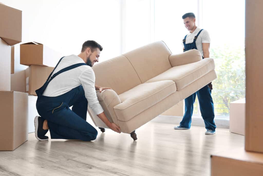 Delivery men moving a sofa in a room at a new home in Long Island, N