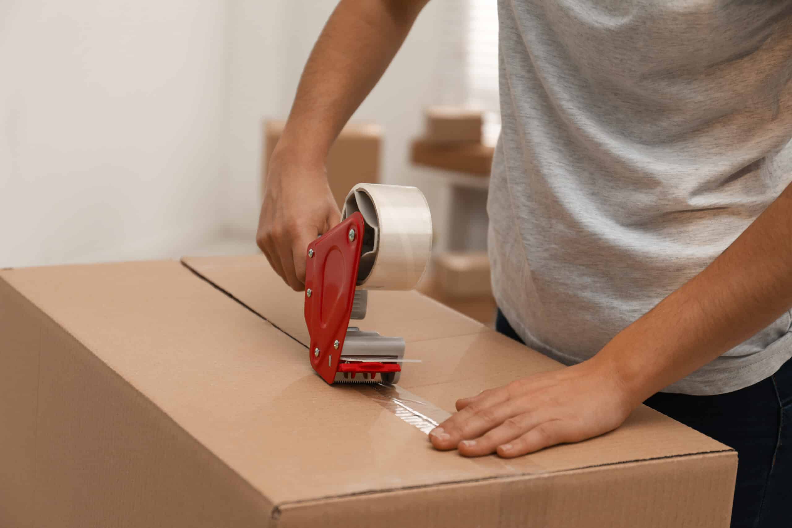 Heavy-duty packing tape being applied to a cardboard box for secure moving.