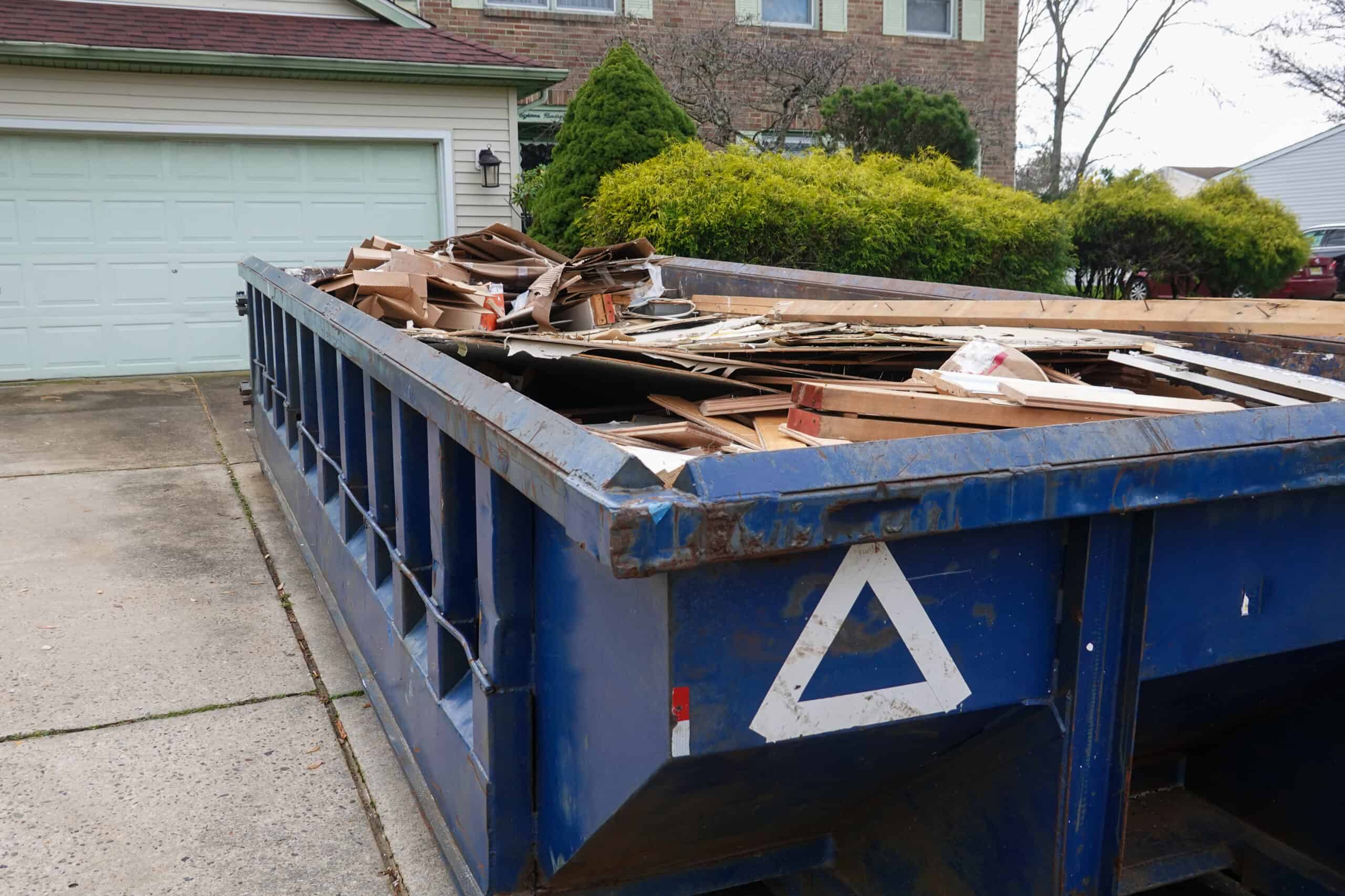 Blue dumpster, recycle waste, and garbage bins near new construction in Long Island, NY.