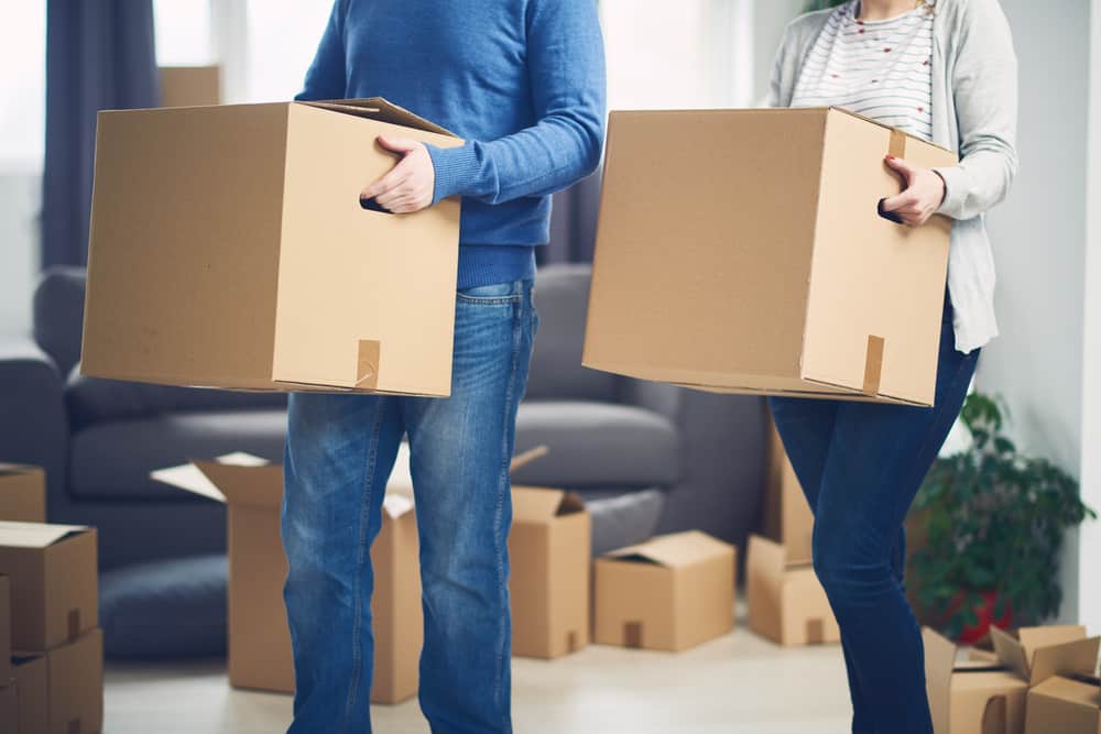 couple moving while holding boxes