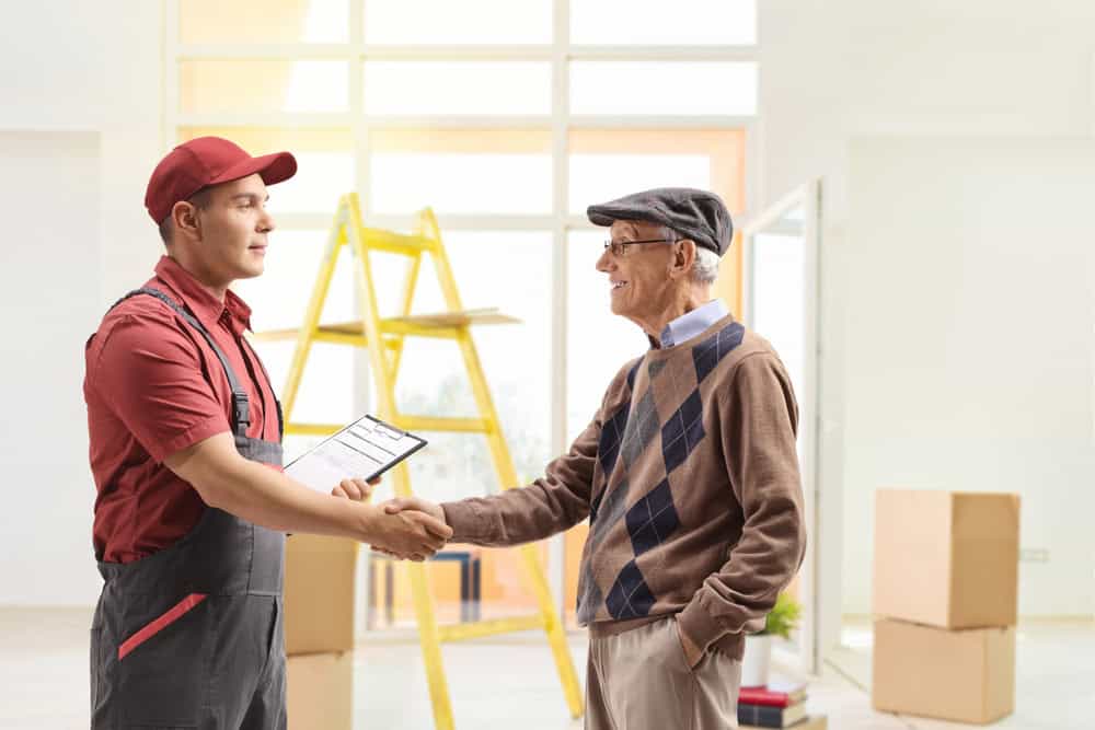 Mover shaking hands with a senior man inside a house in Long Island, NY.